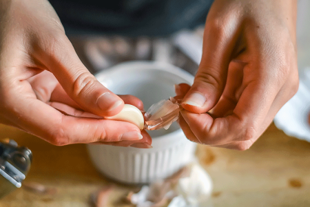 Close-up of woman’s hands peeling garlic, a possible cause of hand eczema.