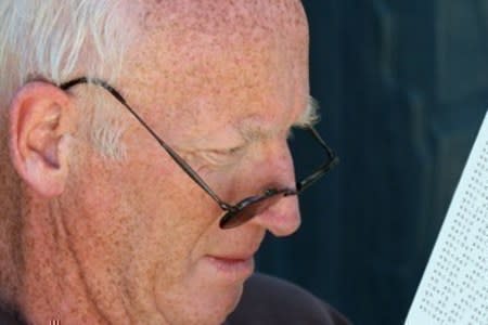 An older man with sun-damaged skin on his forehead, face, and neck