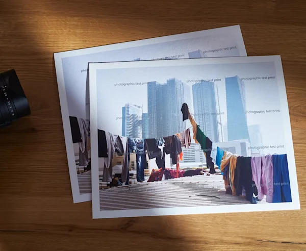Zwei Fine Art Prints mit Testprint-Wasserzeichen auf einem Holztisch liegend