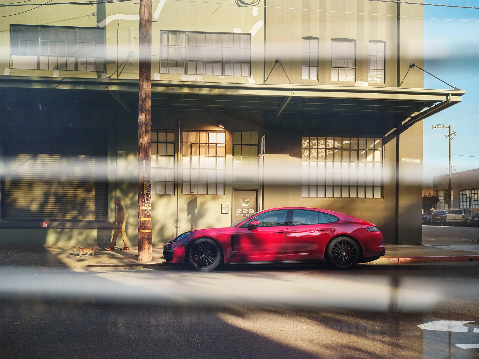 Roter Porsche Panamera GTS vor grüner Industriehalle, gesehen durch Jalousien. Roter Porsche Panamera GTS vor grüner Industriehalle, gesehen durch Jalousien.