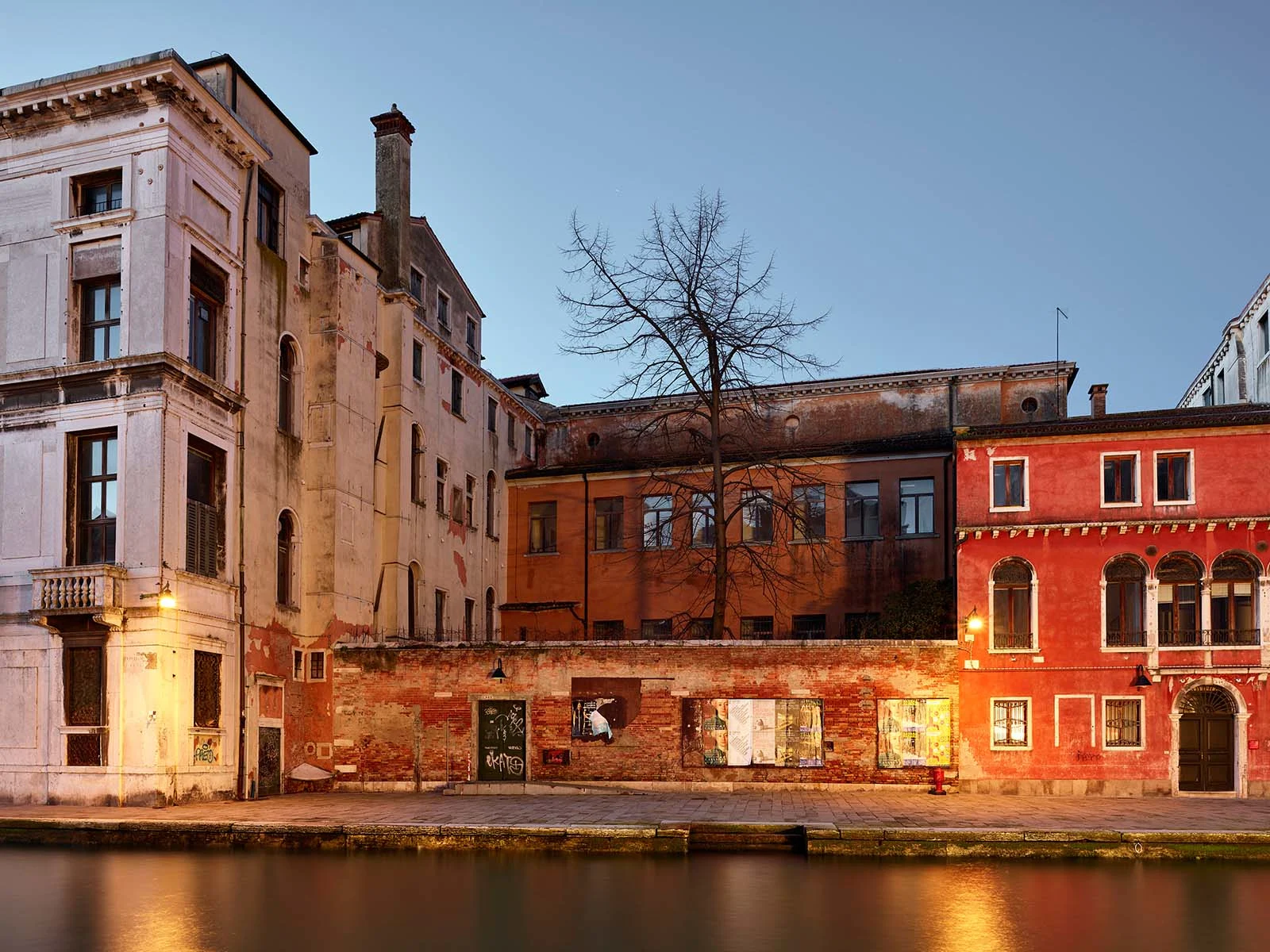 Bâtiment sur le Canale di Cannaregio à Venise dans la lumière du soir, façade rouge, arbre dénudé, eau calme. Bâtiment sur le Canale di Cannaregio à Venise dans la lumière du soir, façade rouge, arbre dénudé, eau calme.
