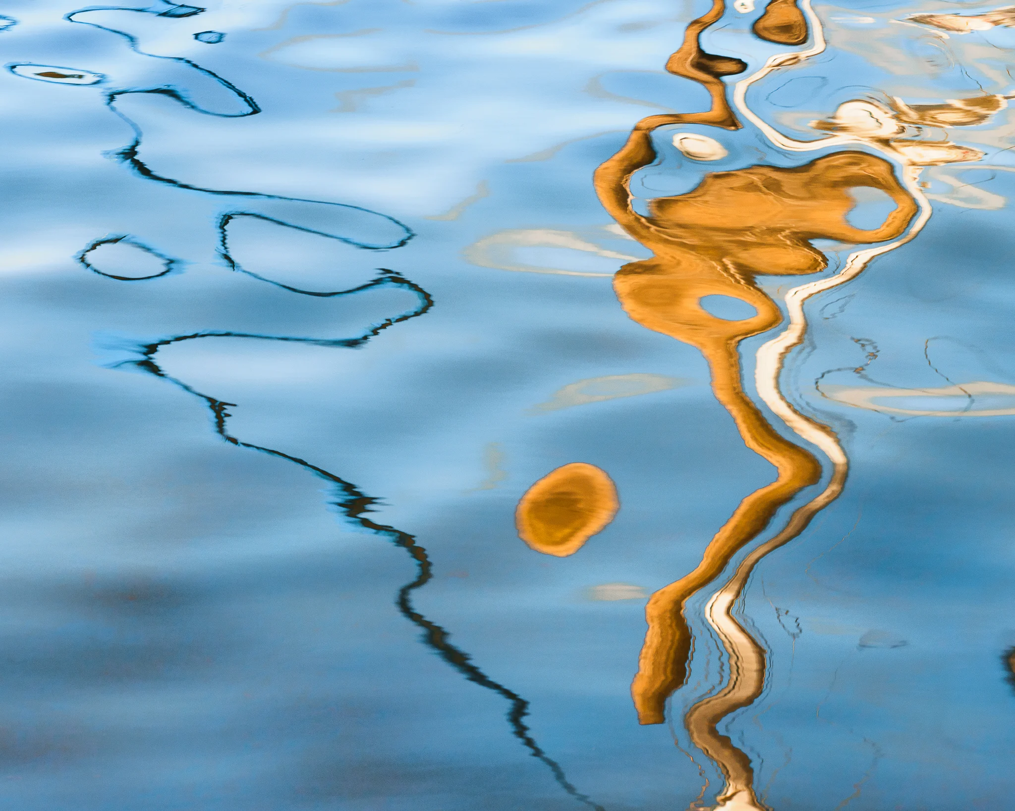 Distorted reflection in blue and gold on moving water. Distorted reflection in blue and gold on moving water.