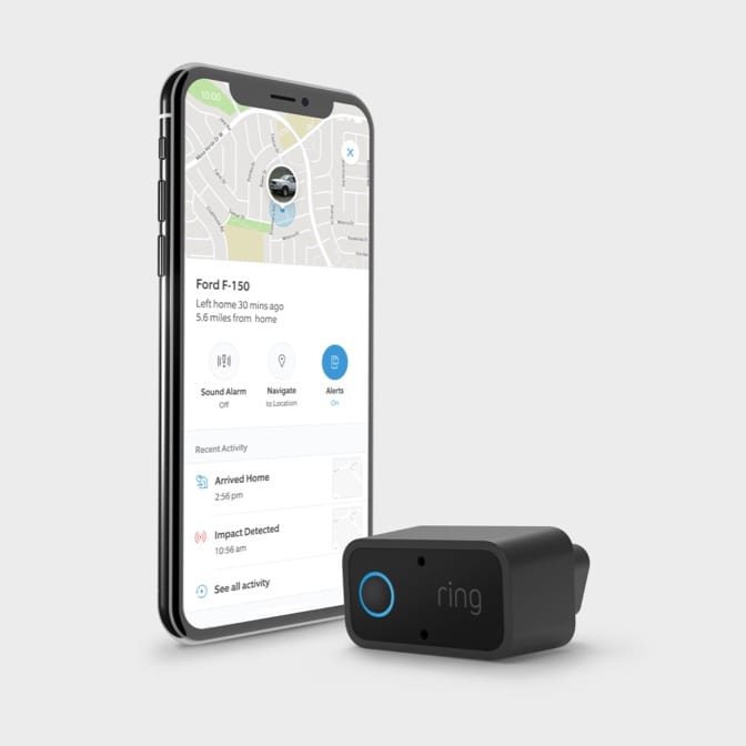 Black Ring Car Alarm with blue ring, beside a smartphone displaying the Ring App with live vehicle tracking interface.