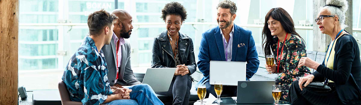 Casual meeting of diverse colleagues with laptops, sitting around a small table with comfortable chairs