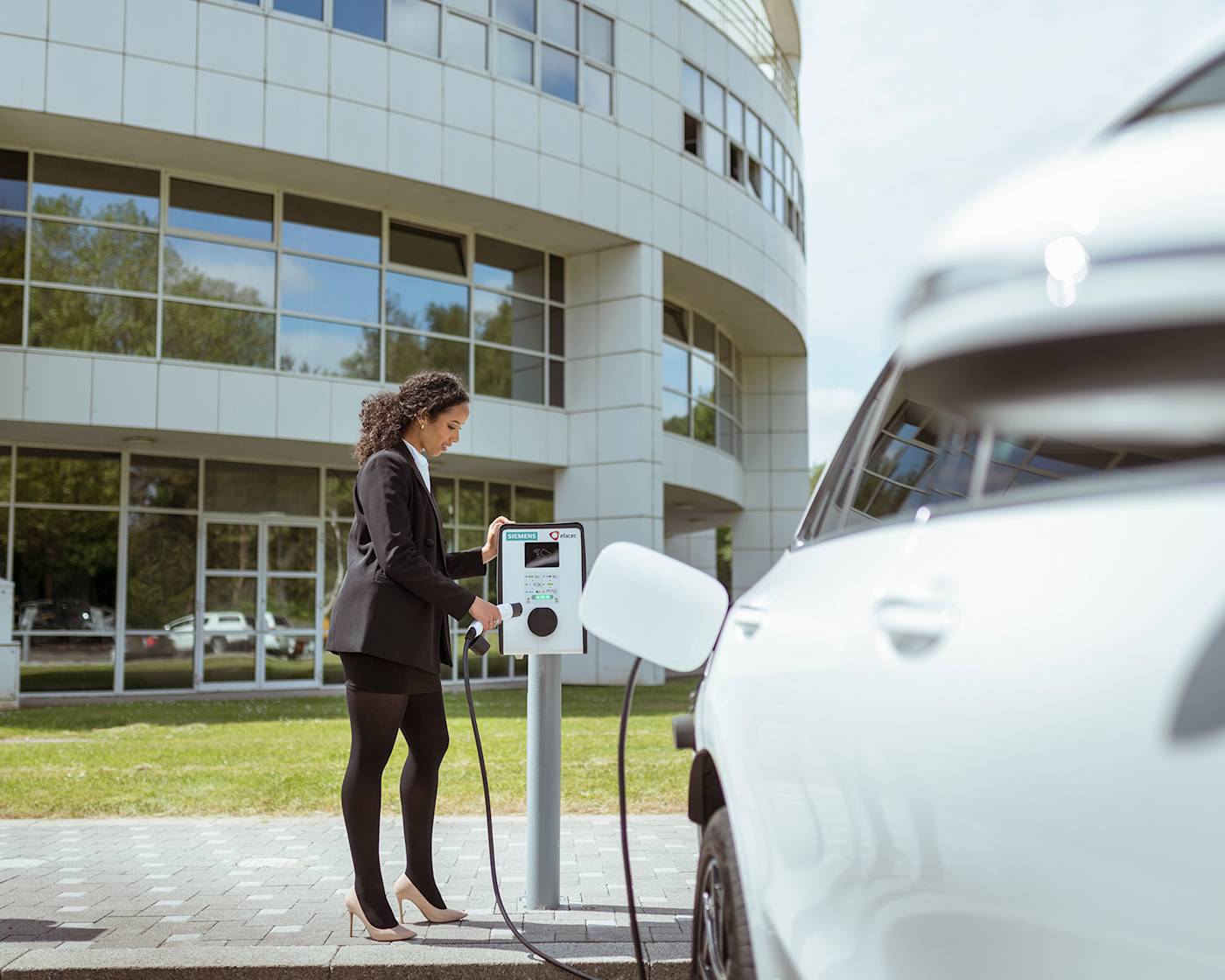 Woman charging white car in business car park