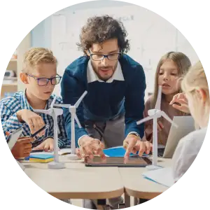 Un gruppo di bambini seduti attorno a un tavolo insieme all’insegnante sono impegnati in un progetto scolastico.