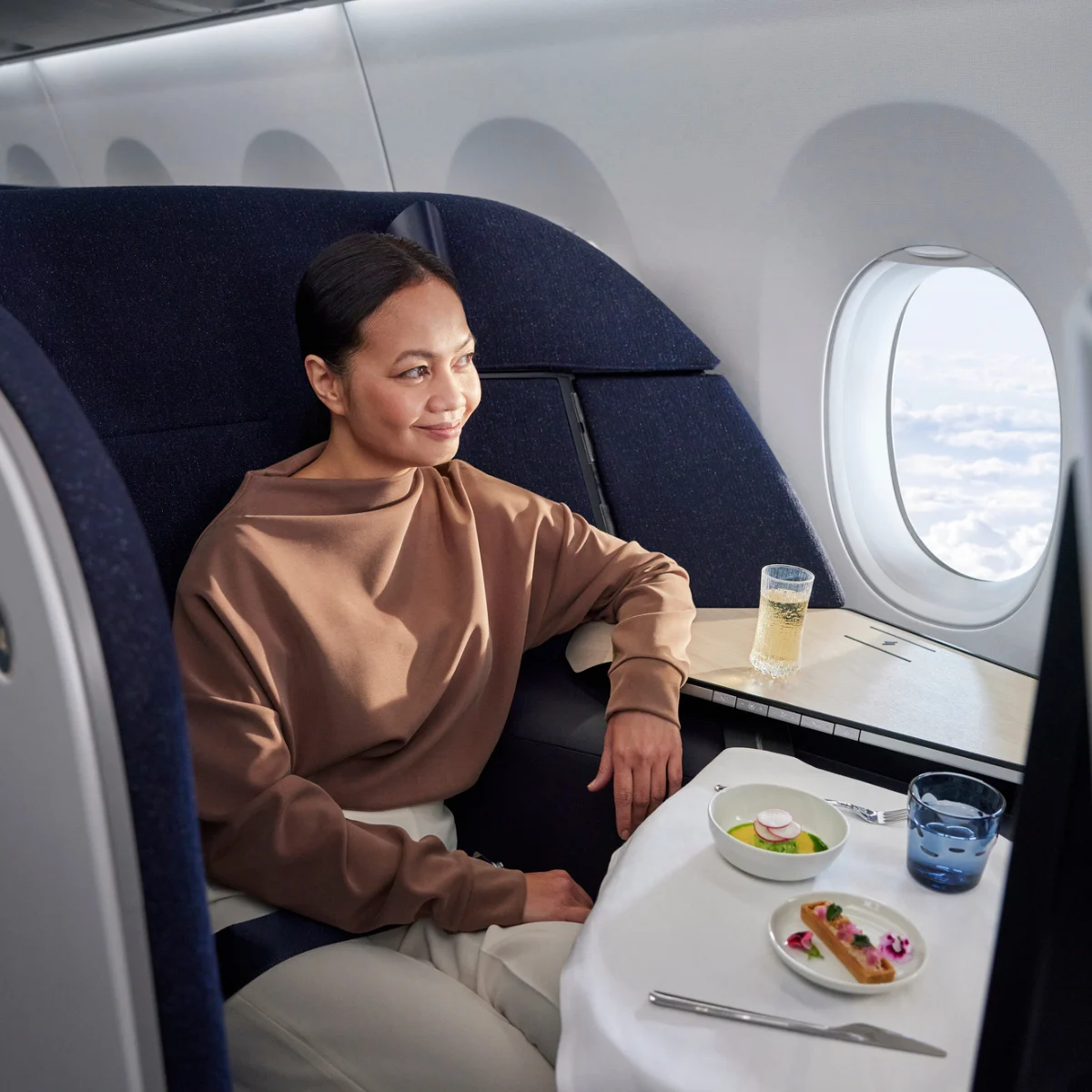 A passenger sits in a large premium class seat on plane.
