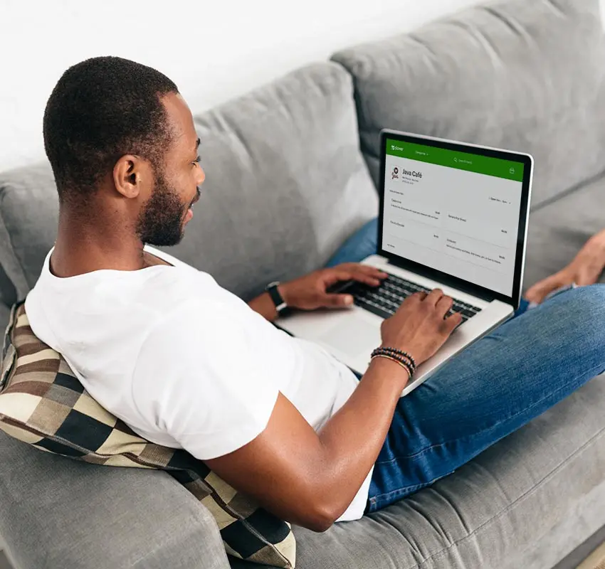 Man sitting on a couch making an online order in his laptop