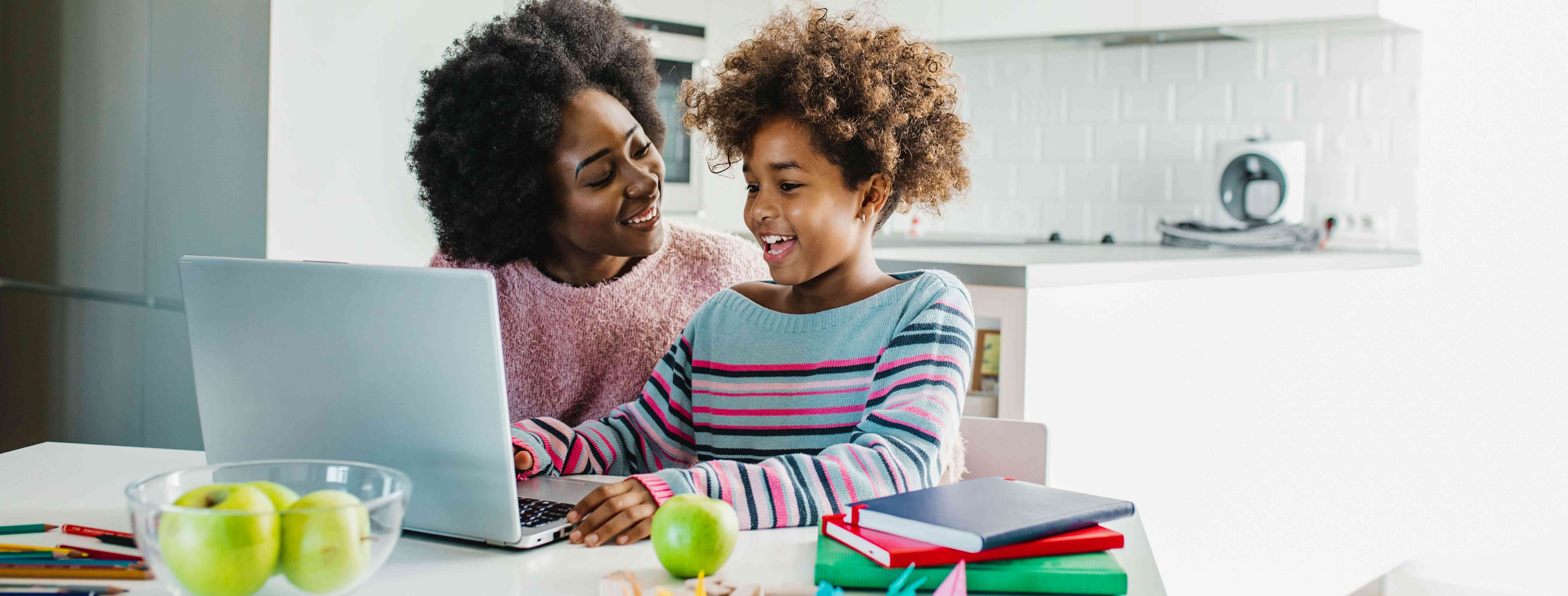 babysitter helping a girl with remote learning assignments.