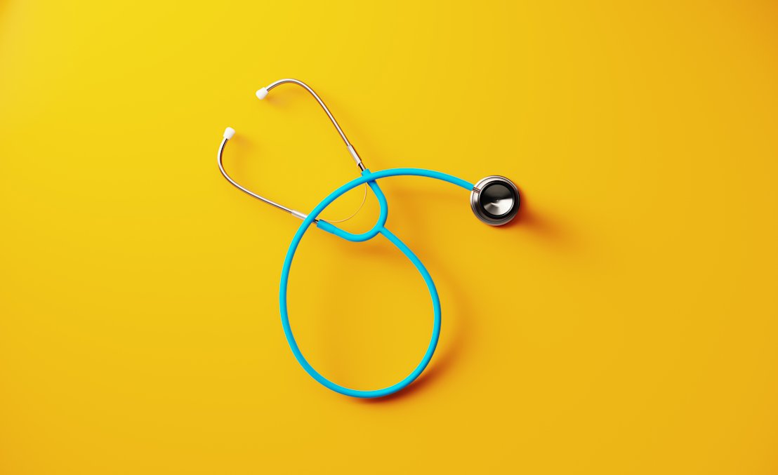 A stethoscope laying on a bright yellow background.