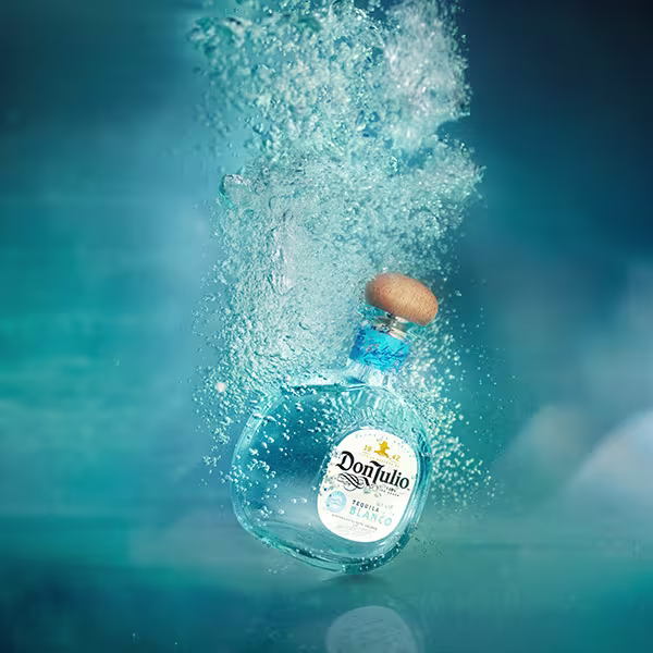 a bottle of Don Julio Blanco submerged in water with bubbles rising from it