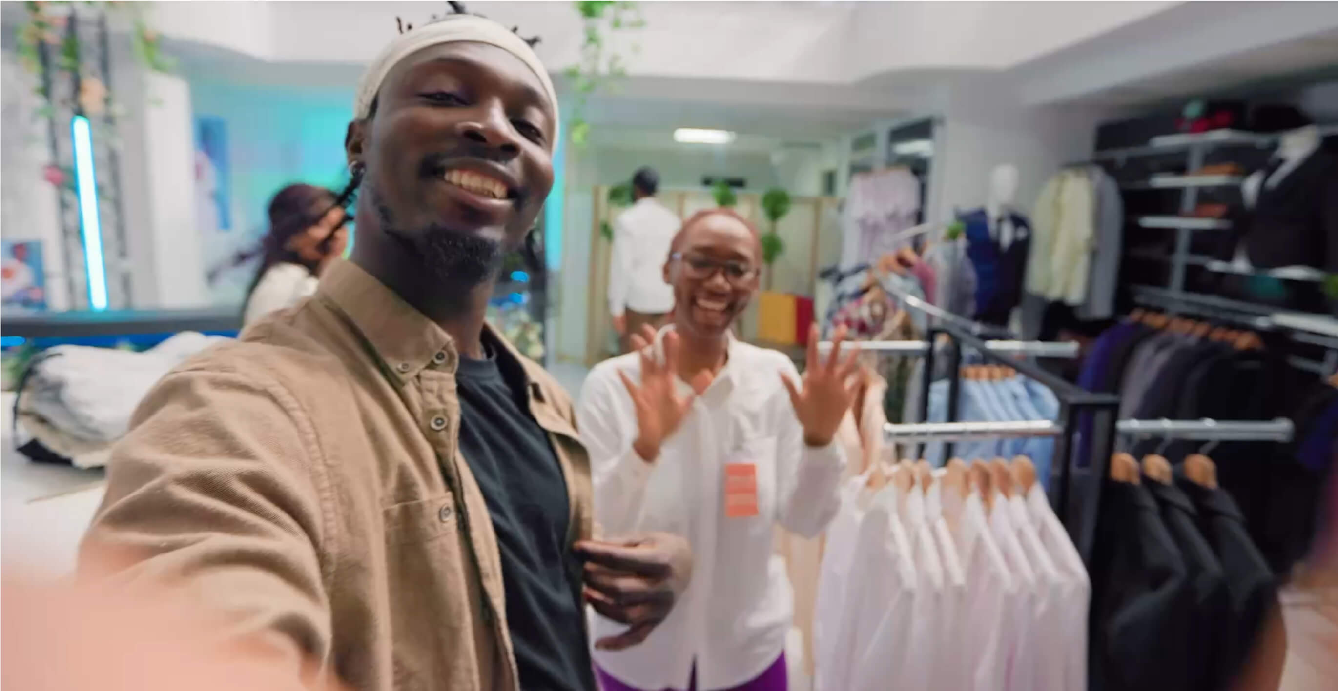 Male and female influencers waving in a fashion clothing store