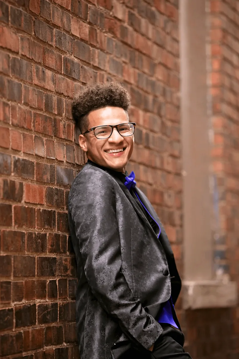 Creator in glasses and black tuxedo with purple bowtie smiles into camera next to key campaign results