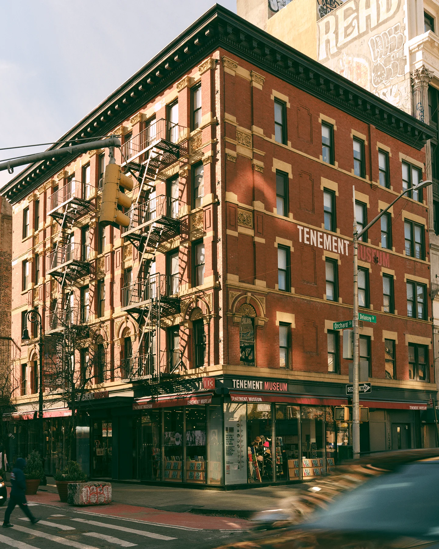A corner of a brick building that five stories tall and has a sign that reads Tenement Museum
