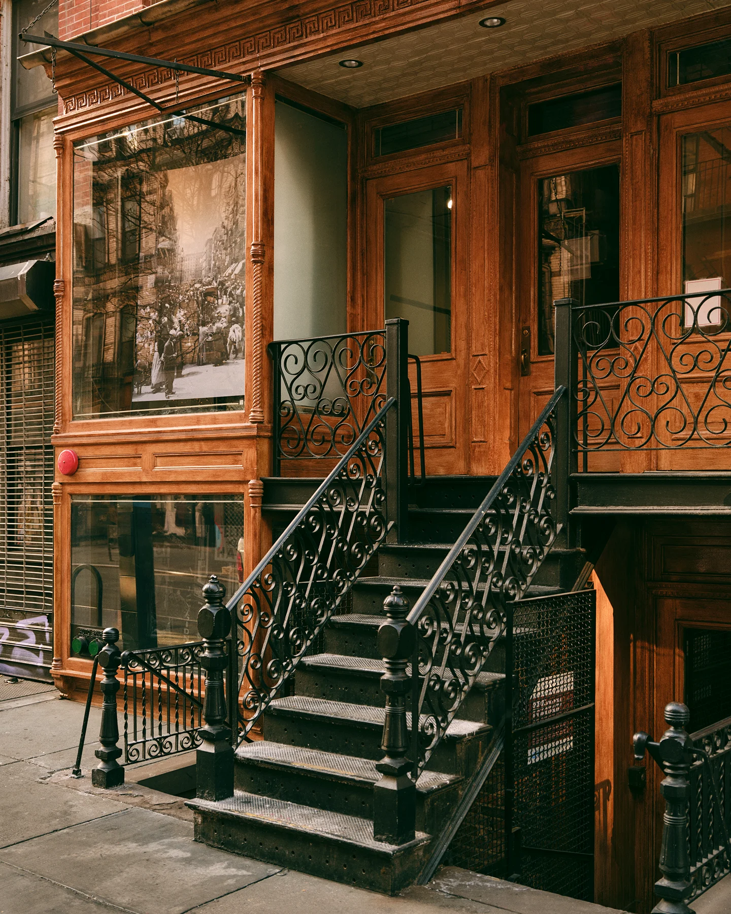 A metal staircase, decorated with ornamental design, connects to a doorway to a tenement apartment building in New York City 
