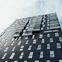 En høy, moderne hotellbygning med mange vinduer, merket "COMFORT HOTEL," står mot en lys, skyet himmel.
