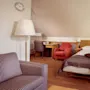Et pent ordnet hotellrom med to enkeltsenger, møbler og varmt lys.
