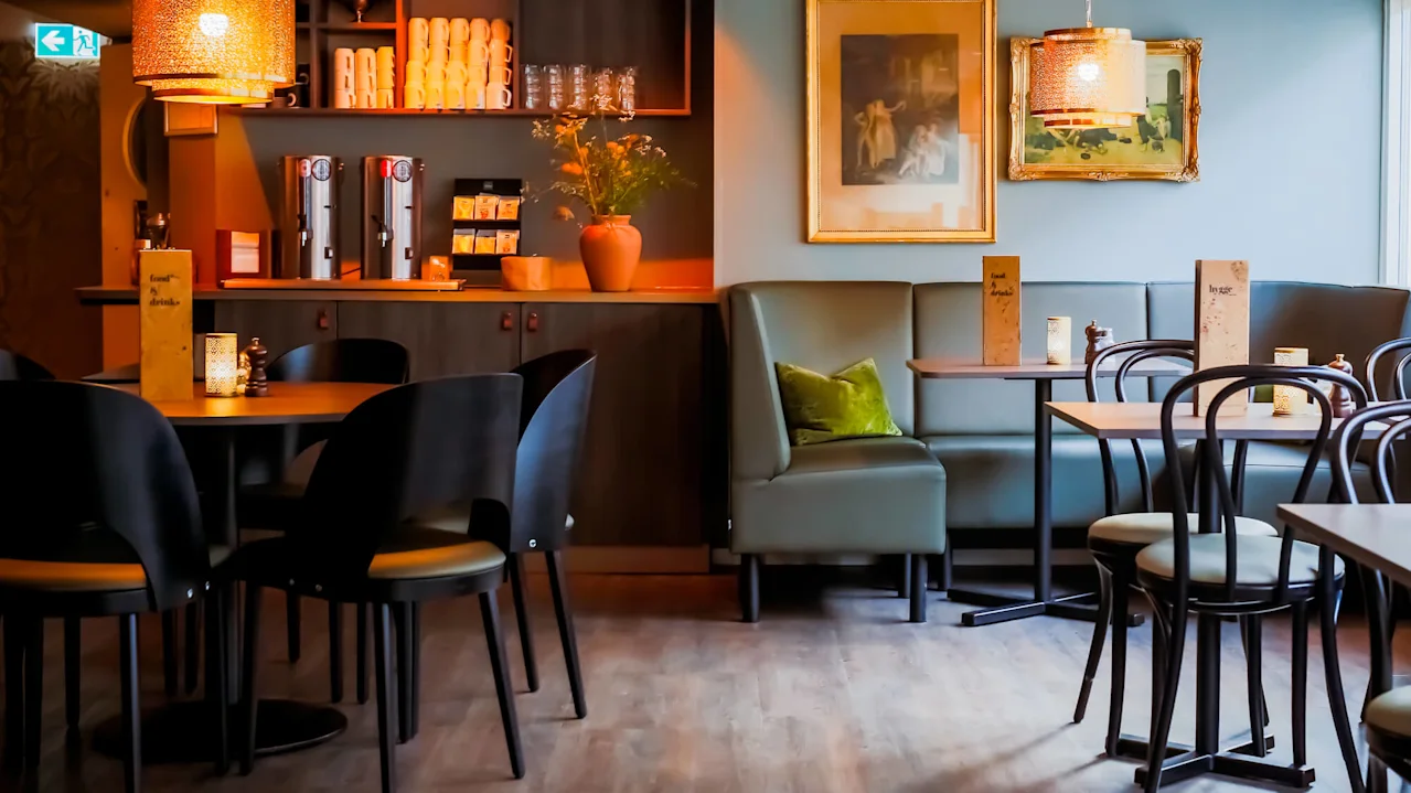 A cozy café interior with empty tables and chairs, ambient lighting, and various decorations.