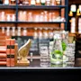 Old books and a golden wing sculpture on a bar counter, with blurry bottles in the background.