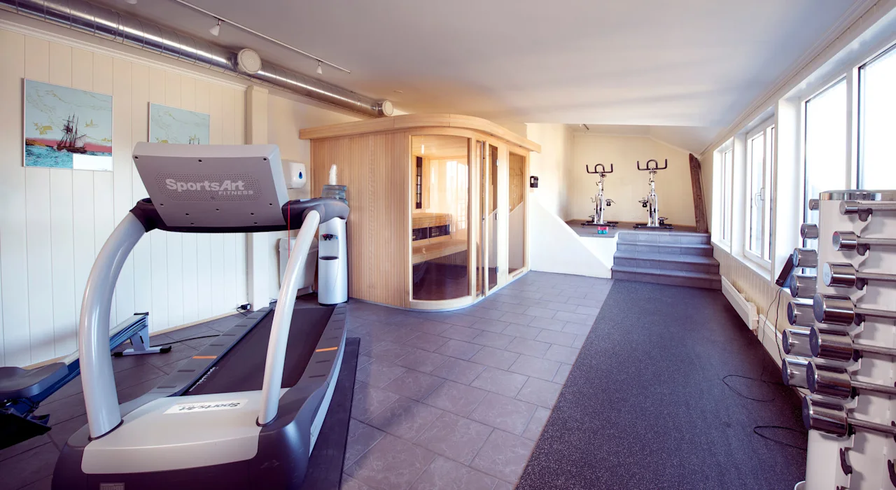 A treadmill, sauna, and exercise bikes in a well-lit, spacious indoor gym.