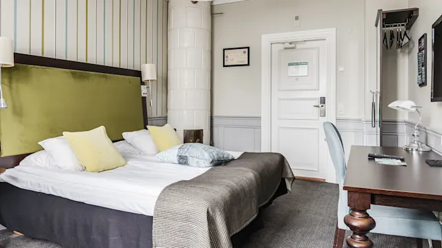 Säng i ett välstädat hotellrum med modern design, randig tapet, inga människor.