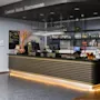 En moderne hotelreception viser snacks og drikkevarer under hængende glas i en godt oplyst lobby. Øverst står skiltet "COMFORT HOTEL KRISTIANSAND."