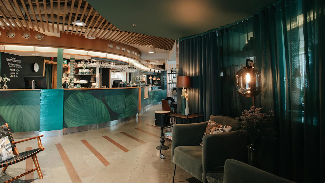 Cozy interior of a cafe with a bar counter, seating, and dim lighting. Ambient, relaxed setting with green and wood accents.