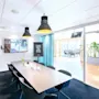 Konferansebord med vannflasker og glass står i et moderne rom. En skjerm viser "ENJOY YOUR CREATIVE MEETING!" Et skilt sier "CLARION LOVES TO THINK OUTSIDE THE BOX!" Store vinduer gir naturlig lys.