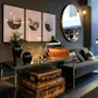 Velvet sofa with pillows, decorative items on tables, framed pictures on wall, large mirror reflects interior of an elegant lounge.
