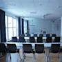 Konferensrum iordningställt med bord och stolar vända mot en whiteboard. Naturligt ljus från fönster, inga personer närvarande.
