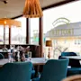 Matbord dukat för servering med glas och kryddor, placerat i ett mysigt kafé med stilfull belysning. Stora fönster visar texten baklänges: "TROTTERS" och "YOUR LOCAL PUB."