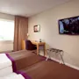 Ett hotellrum med en säng, fåtölj, skrivbord och väggmonterad TV som visar en scen med undertexter: "...skakar lite bra nog."