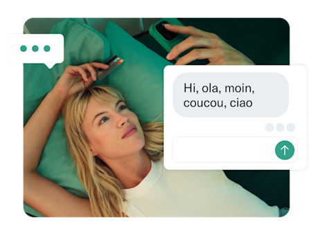 Una donna giace su un letto color verde acqua con un messaggio di auguri in primo piano.