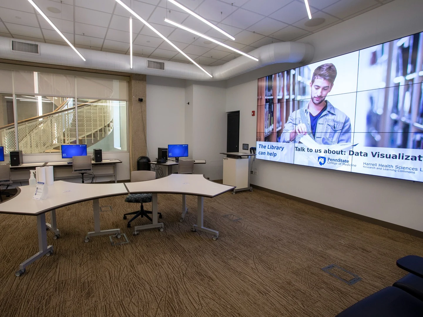 A room inside Harrell Health Sciences Library has workstations and large screen