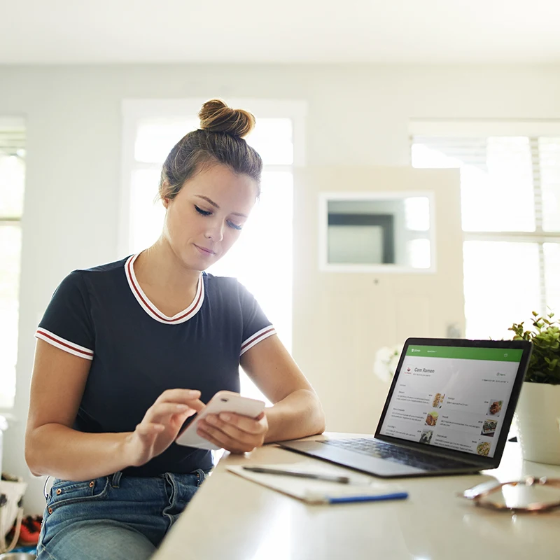 A woman at home using her phone to make an online order