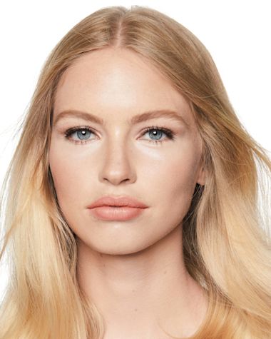 A fair-tone, blonde model wearing glowy, nude makeup with bronzed skin. 