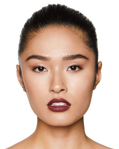 A fair-tone, brunette model wearing a deep berry-rose pink lipstick with a satin finish. 