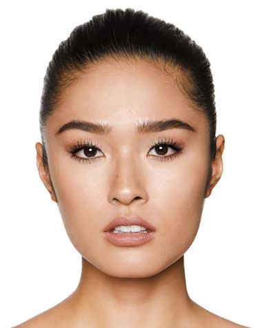 A fair-tone model with brown eyes wearing a jet black volumising mascara that makes her lashes long, defined, and curled. 