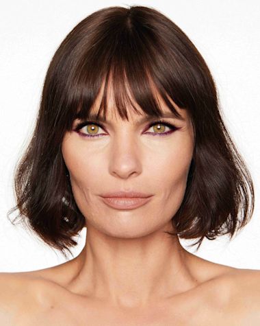 A medium-light-tone model with hazel eyes wearing a matte violet and metallic maroon eyeliner on her eyelid and lower waterline. 