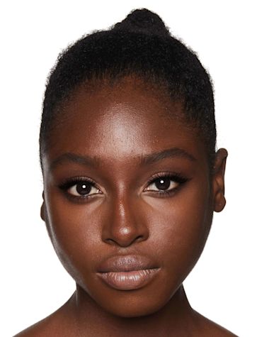 Deep-tone model with brown eyes wearing smokey brown eye makeup with black eyeliner and nude peach lipstick.