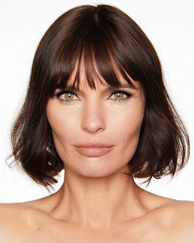 A medium-light-tone model with hazel eyes wearing a jet black volumising mascara that makes her lashes long, defined, and curled. 