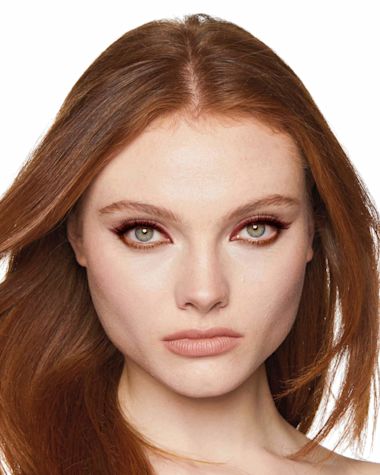 A fair-tone model with grey eyes wearing matte warm-russet and metallic copper eyeliner on her eyelid and lower waterline. 