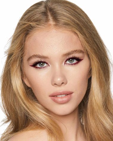 A light-tone model with blue eyes wearing a matte violet and metallic maroon eyeliner on her eyelid and lower waterline. 