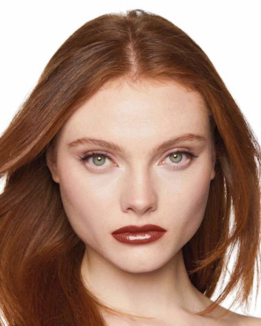 Fair-tone model with grey eyes wearing a moisturising lipstick balm in a soft brown shade with a high-shine finish.