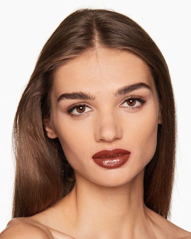 Medium-tone model with brown eyes wearing a moisturising lipstick balm in a soft brown shade with a high-shine finish.