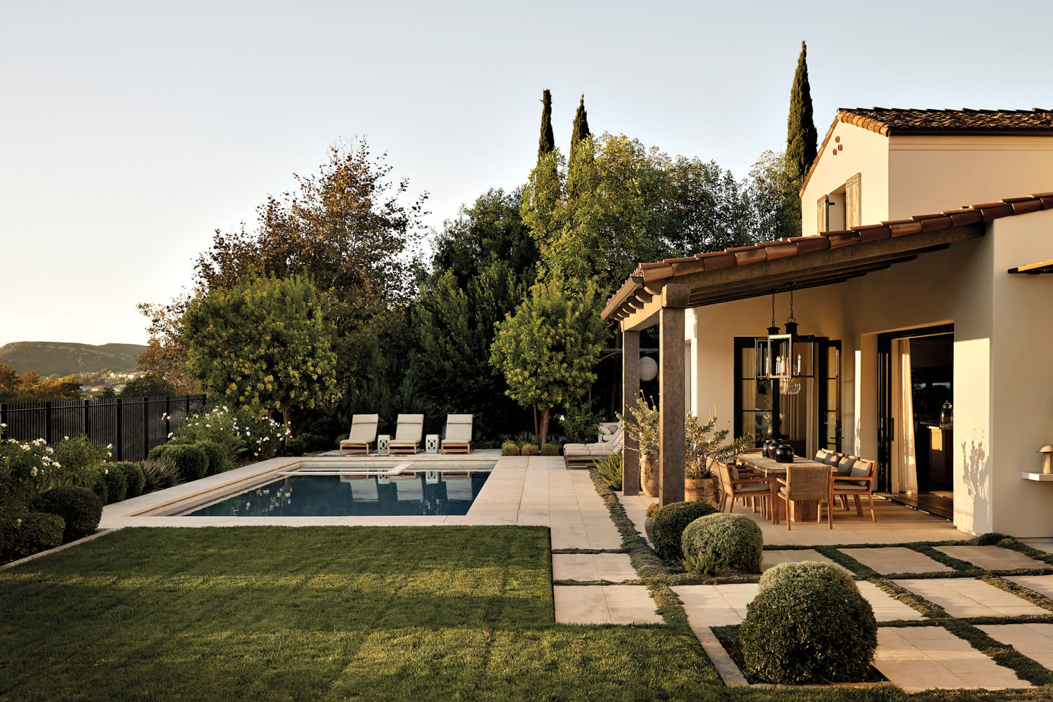 backyard with pool surrounded by trees, lounge chairs, vintage Chinese garden stools and a covered outdoor dining area