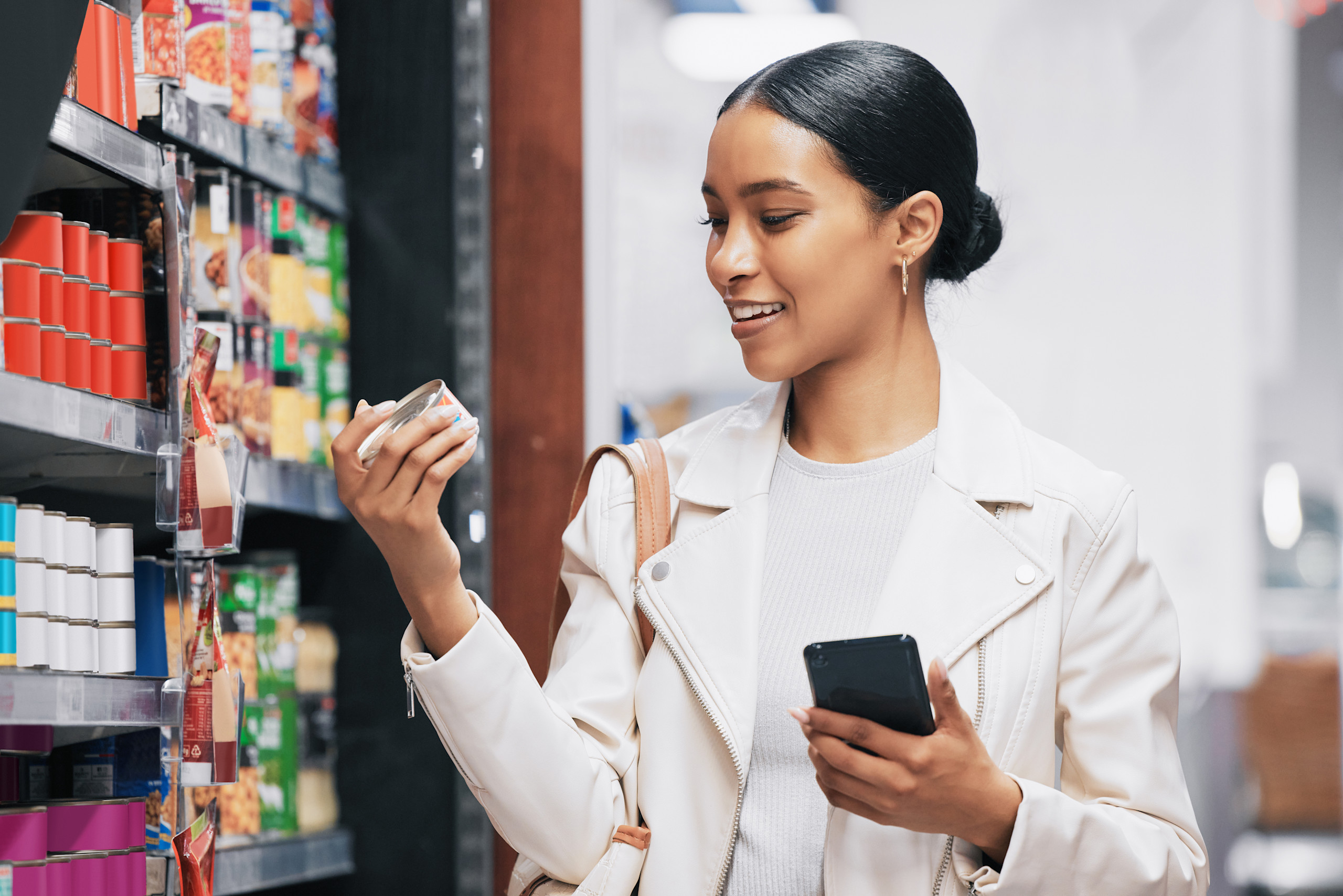 Woman reading promoted product in grocery store holding phone in hand.