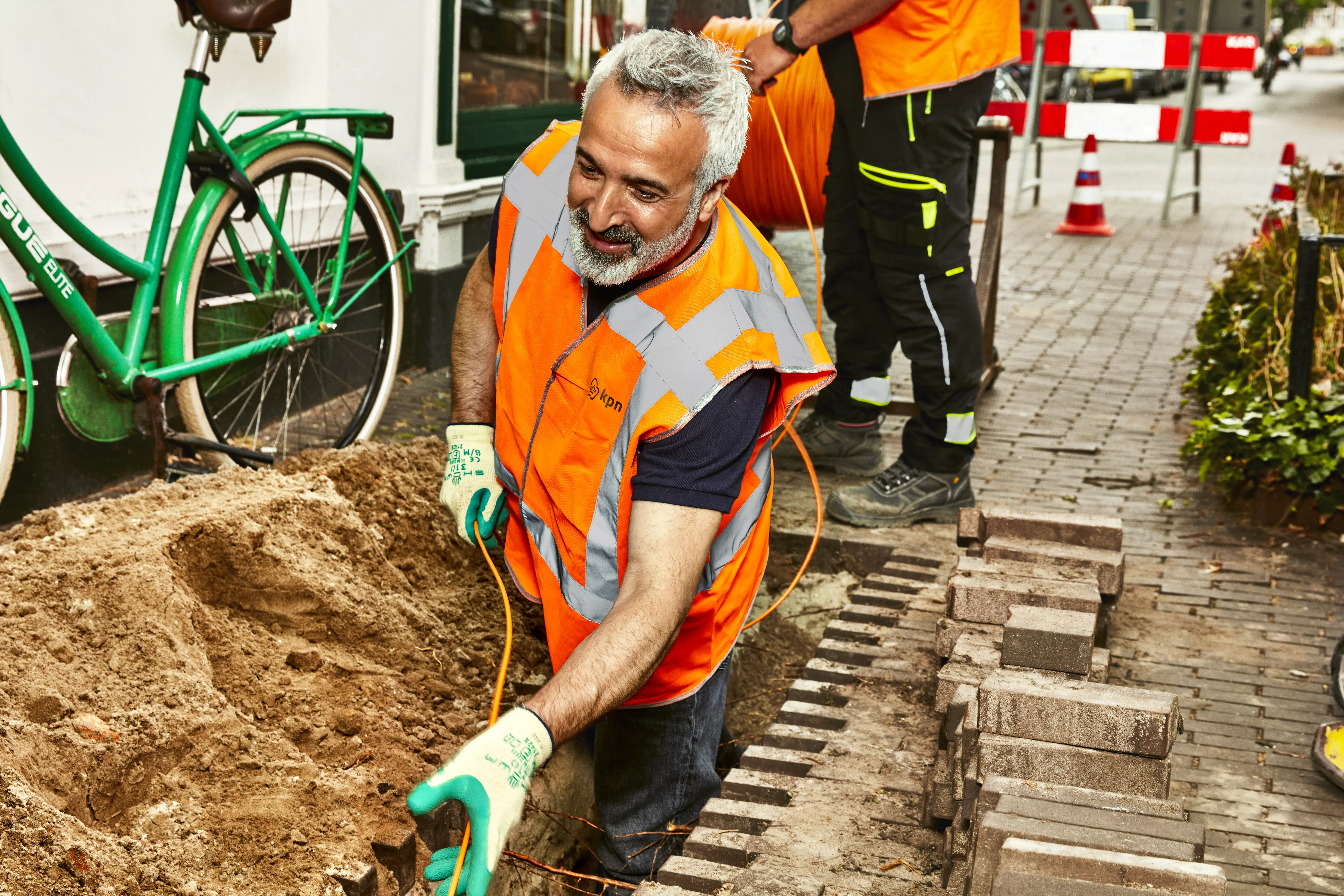 Twee mannen leggen glasvezel aan in een open gegraven straat