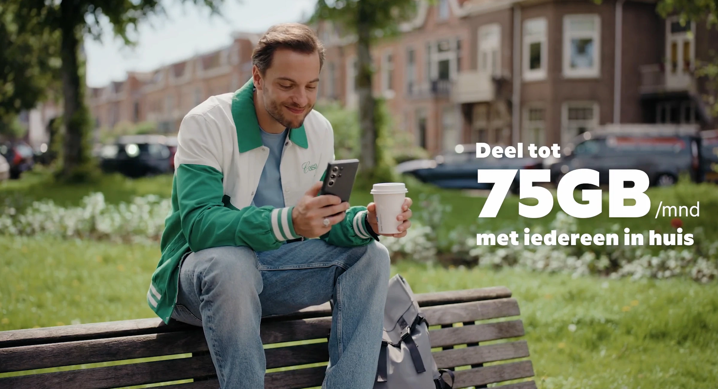 Man die buiten op een bankje zit met in zijn ene hand een telefoon en in de andere een koffie to go. Op de afbeelding staat de tekst 'Deel tot 75GB pet maand met iedereen in huis.'
